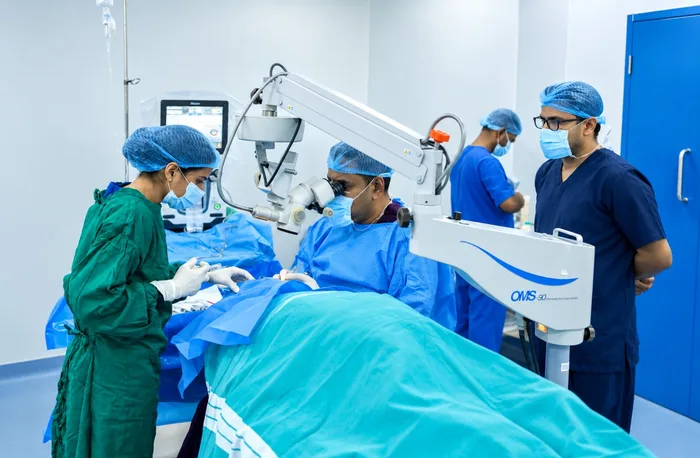 Surgeon performing ophthalmic microsurgery with operating microscope and sterile surgical team